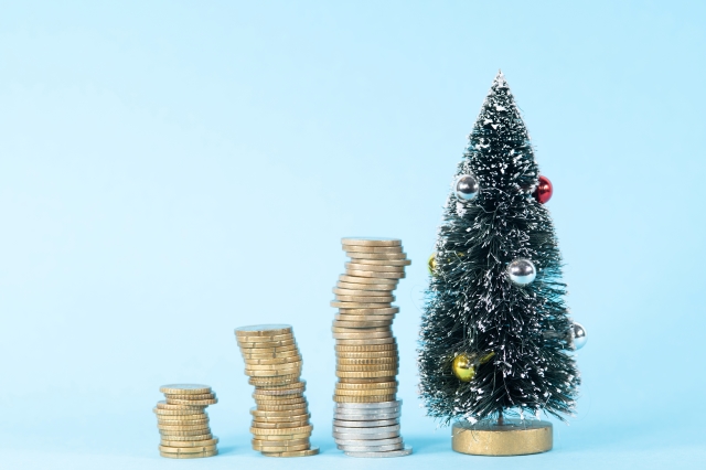 A small Christmas tree next to piles of coins 