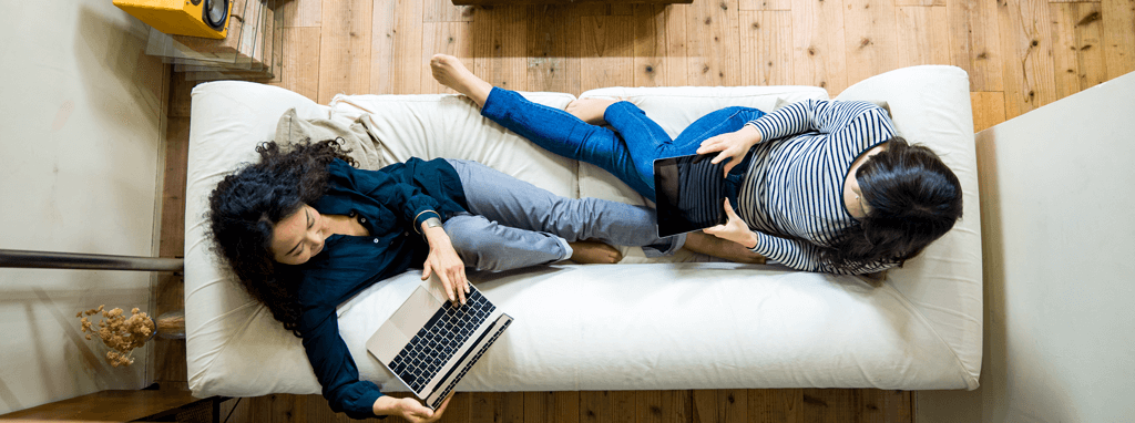 Women on sofa using technology