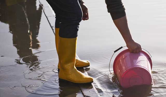 Person in boots in a puddle with bucket